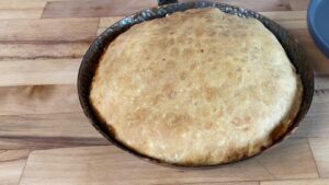 A Golden-Brown Pastry Crust Sits Atop a Pan of Baked Tarte Tatin, Ready to Be Flipped and Served