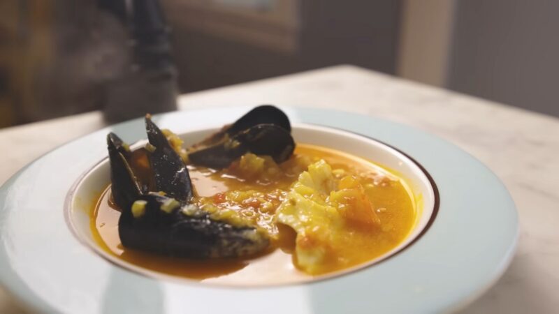 A rich, flavorful bowl of bouillabaisse featuring mussels, fish, and a saffron-infused broth